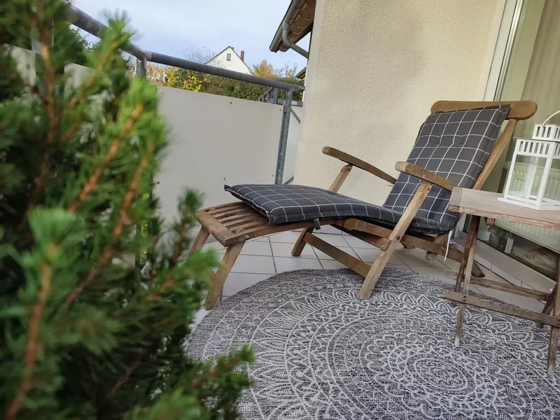 Balkon mit Holz-Liegestuhl und Pflanzen