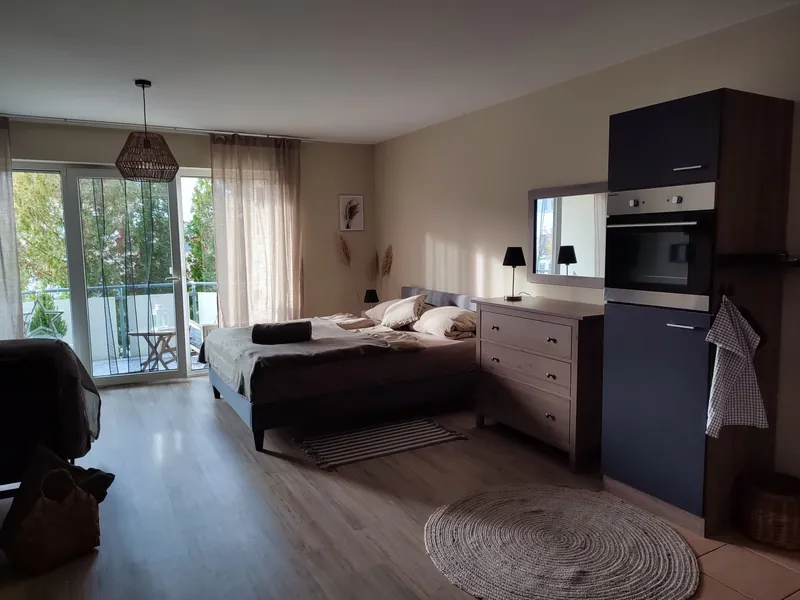 Heller, skandinavisch eingerichteter Wohn-/Schlafraum mit Doppelbett, Balkonzugang und Küchenzeile – Ferienwohnung Apartment Kümmel in Eichenzell