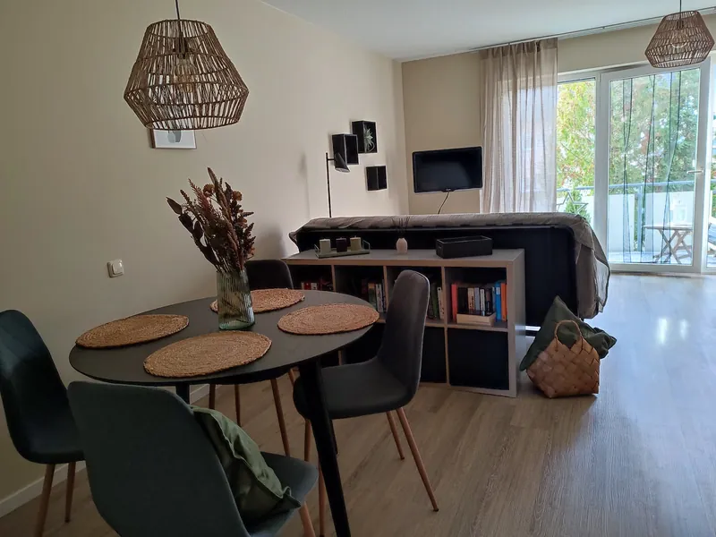 Helles Wohnbereich mit Sofa, Fernseher und Balkonzugang – Ferienwohnung Eichenzell